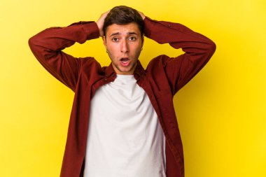 Sarı arka planda izole edilmiş dövmeleri olan genç beyaz adam şaşırdı ve şok oldu..