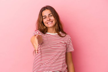 Pembe arka planda izole edilmiş beyaz bir kadın. Kameraya elini uzatıp selam veriyor..