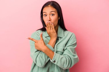 Pembe arka planda izole edilmiş genç Latin kadın yan tarafı gösteriyor.