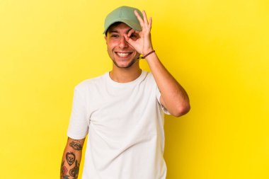 Sarı arka planda izole edilmiş beyaz dövmeli genç bir adam heyecanlı..