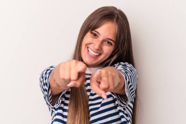 Beyaz arka planda izole edilmiş genç beyaz kadın parmaklarıyla ön tarafı işaret ediyor..