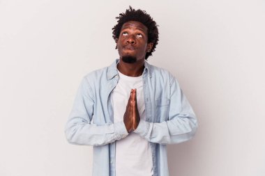 Beyaz arka planda izole edilmiş genç Afro-Amerikan bir adam el ele tutuşup dua ederken kendine güveniyor..