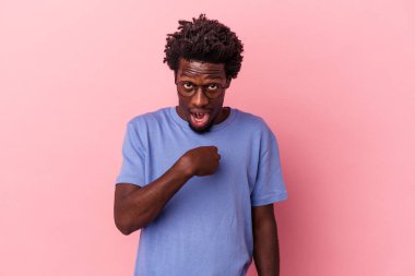 Pembe arka planda izole edilmiş genç Afro-Amerikalı adam parmağını göstererek şaşırdı ve gülümsedi..