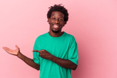 Pembe arka planda izole edilmiş genç bir Afro-Amerikan erkeği Palm 'da bir fotokopi alanı tutarken heyecanlı..