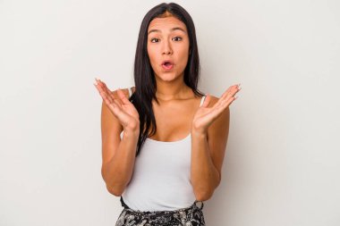 Beyaz arka planda yalnız yaşayan genç Latin kadın şaşırdı ve şok oldu..