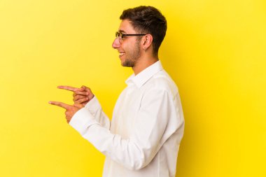 Sarı arka planda dövmeleri olan genç beyaz bir adam. Baş parmak uzakta, gülüyor ve kaygısız..