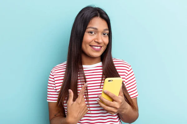 Ung Venezuelansk Kvinna Som Håller Mobiltelefon Isolerad Blå Bakgrund Pekar — Stockfoto