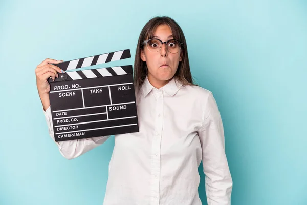 Young Caucasian Woman Holding Clapperboard Isolated Blue Background Shrugs Shoulders — Stock Photo, Image