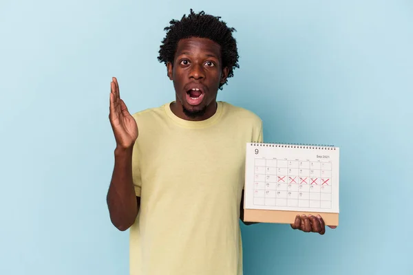 Mladý Africký Američan Drží Kalendář Izolované Modrém Pozadí Překvapen Šokován — Stock fotografie