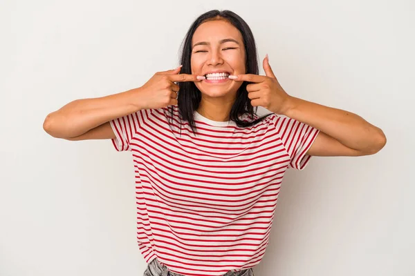 Beyaz arka planda izole edilmiş genç Latin kadın gülümsüyor, parmaklarını ağıza doğrultuyor..