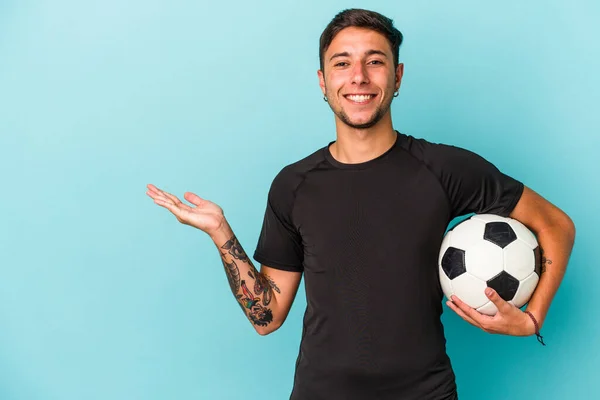 Молодий Чоловік Грає Футбол Тримаючи Ізольований Синьому Фоні Показуючи Простір — стокове фото