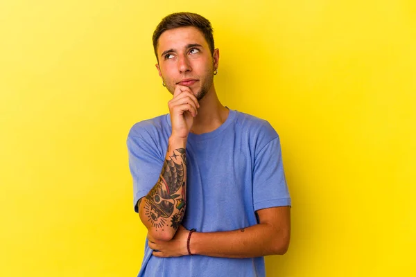 Young Caucasian Man Tattoos Isolated Yellow Background Relaxed Thinking Something —  Fotos de Stock