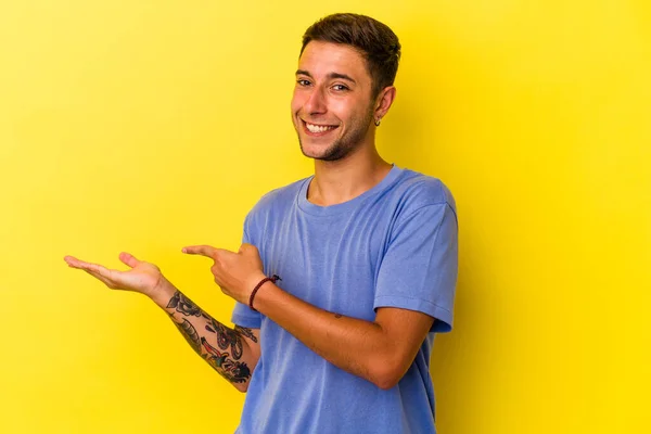Νεαρός Καυκάσιος Άνδρας Τατουάζ Απομονωμένα Κίτρινο Φόντο Ενθουσιασμένος Κρατώντας Ένα — Φωτογραφία Αρχείου