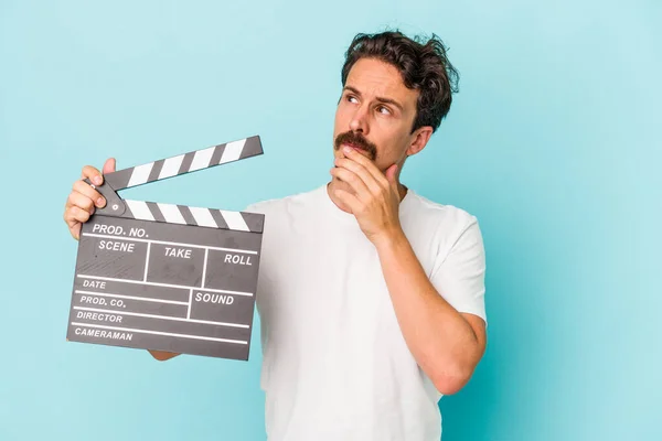 Young Caucasian Man Holding Clapperboard Isolated Blue Background Looking Sideways — Stock Photo, Image