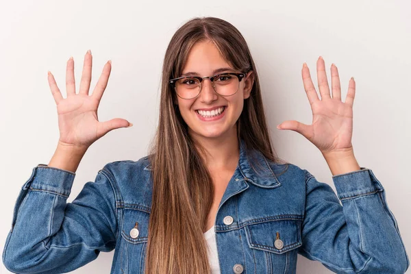 Beyaz arka planda izole edilmiş beyaz tenli genç kadın on numarayı elleriyle gösteriyor..