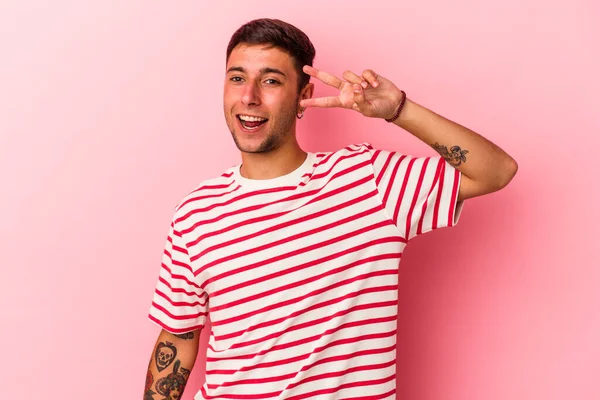 Sarı arka planda izole edilmiş dövmeleri olan genç beyaz adam dans ediyor ve eğleniyor..