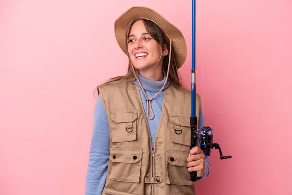 Young Caucasian Fisherwoman Holding Rod Isolated Pink Background Looks Aside — Stock Photo, Image
