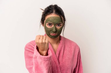 Young caucasian woman wearing a facial mask isolated on white background showing fist to camera, aggressive facial expression.