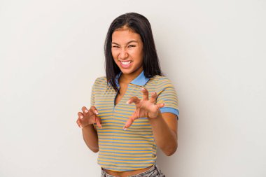 Beyaz arka planda izole edilmiş genç Latin kadın pençelerini kedi taklidi yaparken gösteriyor, agresif bir hareket..