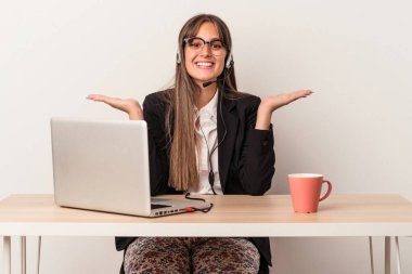 Beyaz arka planda izole bir şekilde seyahat eden beyaz tenli genç bir kadın kollarıyla ölçek oluşturuyor, mutlu ve kendinden emin hissediyor..