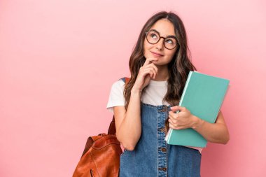 Young caucasian student woman isolated on pink background looking sideways with doubtful and skeptical expression.