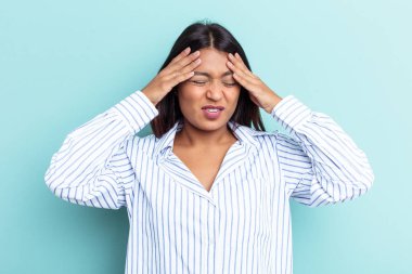 Genç Venezuelalı kadın mavi arka planda izole edilmiş tapınaklara dokunuyor ve baş ağrısı çekiyor..