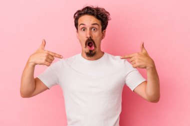 Pembe arka planda izole edilmiş genç beyaz adam parmaklarıyla aşağıya doğru, olumlu bir his..