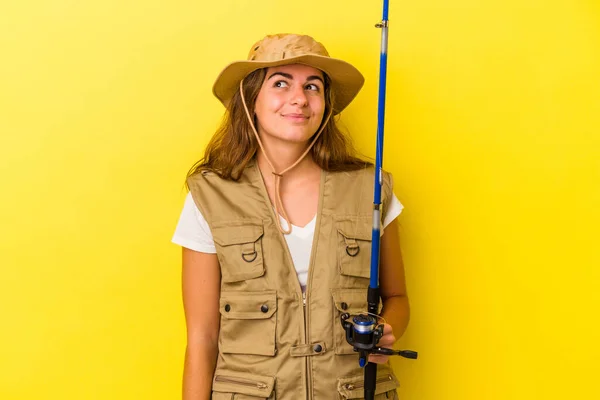 年轻的高加索女渔民手持一根因黄色背景而被隔离的钓竿 梦想着实现自己的目标和宗旨 — 图库照片