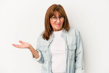 Beyaz arka planda soyutlanmış orta yaşlı beyaz bir kadın sorgulama sırasında omuz silkiyor ve şüphe duyuyor..