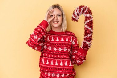 Sarı arka planda büyük bir noel sopası tutan beyaz bir kadın heyecanlı..