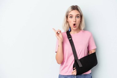 Kırık elli beyaz bir kadın. Mavi arka planda izole edilmiş. Yan tarafı gösteriyor.