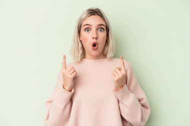 Yeşil arka planda izole edilmiş beyaz bir kadın ağzı açık bir şekilde üst tarafı işaret ediyor..