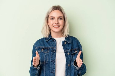 Yeşil arka planda izole edilmiş beyaz bir kadın iki eliyle bir şey tutuyor, ürün sunumu..