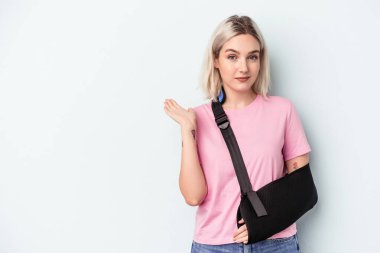 Kırık elli beyaz bir kadın mavi arka planda izole edilmiş. Bir avuç içinde fotokopi alanı var ve belinde başka bir el tutuyor..