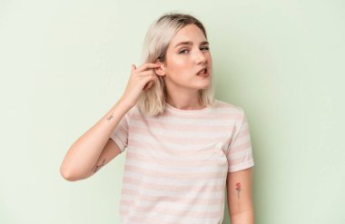 Genç beyaz kadın yeşil arka planda izole edilmiş parmaklarıyla kulaklarını kapatıyor, gürültülü bir ortam yüzünden stresli ve çaresiz..