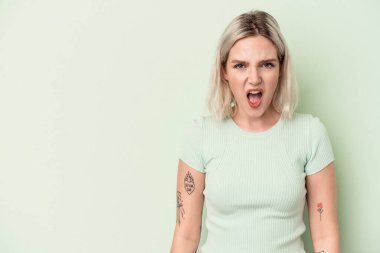 Yeşil arka planda izole edilmiş genç beyaz kadın çok kızgın, öfkeli, hayal kırıklığına uğramış.