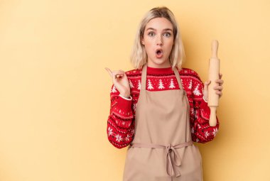 Kafkasyalı genç fırıncı kadın Noel için kurabiye yapıyor. Sarı arka planda izole edilmiş. Yan tarafı gösteriyor.