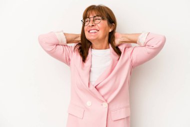 Beyaz arka planda soyutlanmış orta yaşlı beyaz bir kadın kendini güvende hissediyor, elleri başının arkasında..