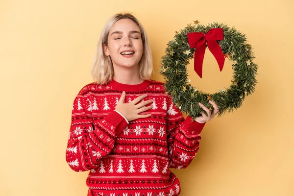 Young Caucasian Woman Holding Christmas Wreath Isolated Yellow Background Laughs — Stock Photo, Image