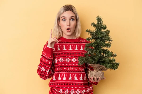 Mladá Běloška Drží Malý Vánoční Stromek Izolované Žlutém Pozadí Nápadem — Stock fotografie
