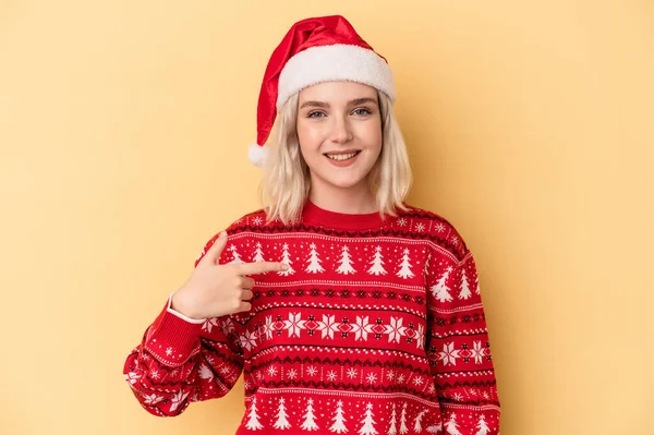 若いです白人女性を祝いますクリスマスは黄色の背景の人に孤立しました手でシャツのコピースペースを指しています 誇りと自信 — ストック写真
