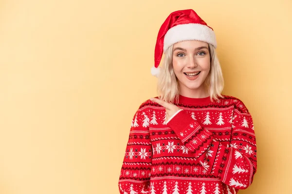 黄色の背景に孤立したクリスマスを祝う若い白人女性笑顔と脇を指して 空白のスペースで何かを示す — ストック写真