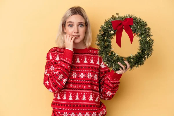 Young Caucasian Woman Holding Christmas Wreath Isolated Yellow Background Biting — Foto Stock