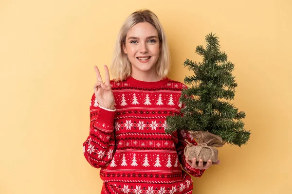 Mladá Běloška Drží Malý Vánoční Stromek Izolované Žlutém Pozadí Ukazující — Stock fotografie