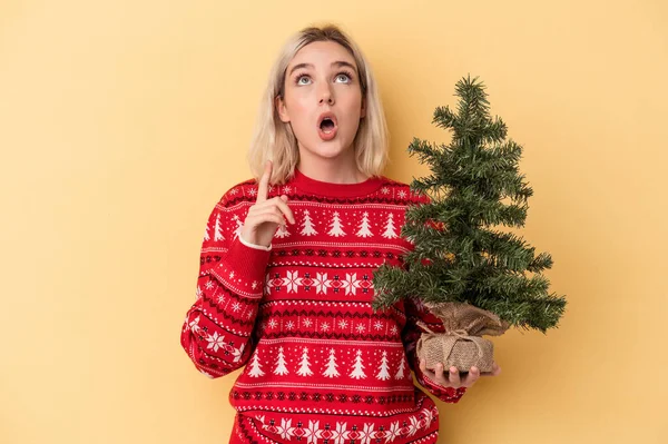 Jonge Blanke Vrouw Met Een Kleine Kerstboom Geïsoleerd Gele Achtergrond — Stockfoto