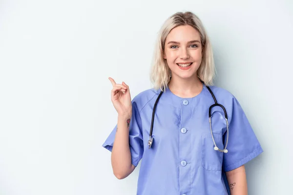 Ung Sjuksköterska Kvinna Isolerad Blå Bakgrund Ler Och Pekar Sidan — Stockfoto