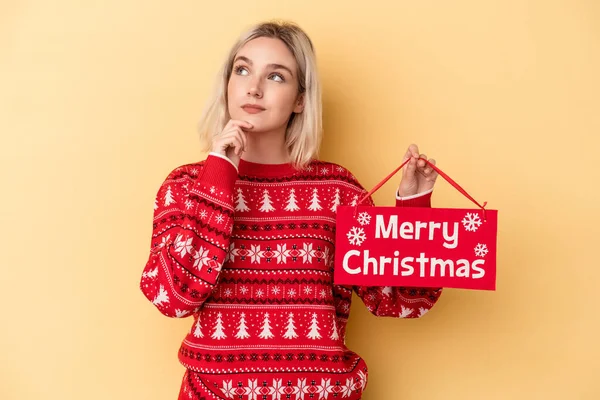 Mladá Běloška Drží Veselý Vánoční Plakát Izolovaný Žlutém Pozadí Dívá — Stock fotografie
