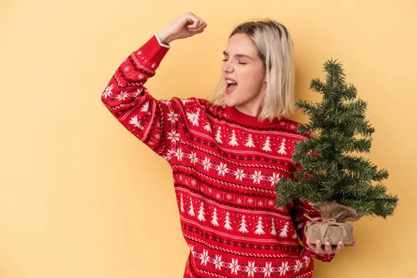 Mladá Běloška Drží Malý Vánoční Stromek Izolované Žlutém Pozadí Zvedající — Stock fotografie