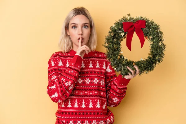 Mladá Běloška Drží Vánoční Věnec Izolovaný Žlutém Pozadí Udržuje Tajemství — Stock fotografie