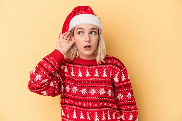 若いです白人女性祝いますクリスマスは黄色の背景に隔離されましたゴシップを聞こうとして — ストック写真